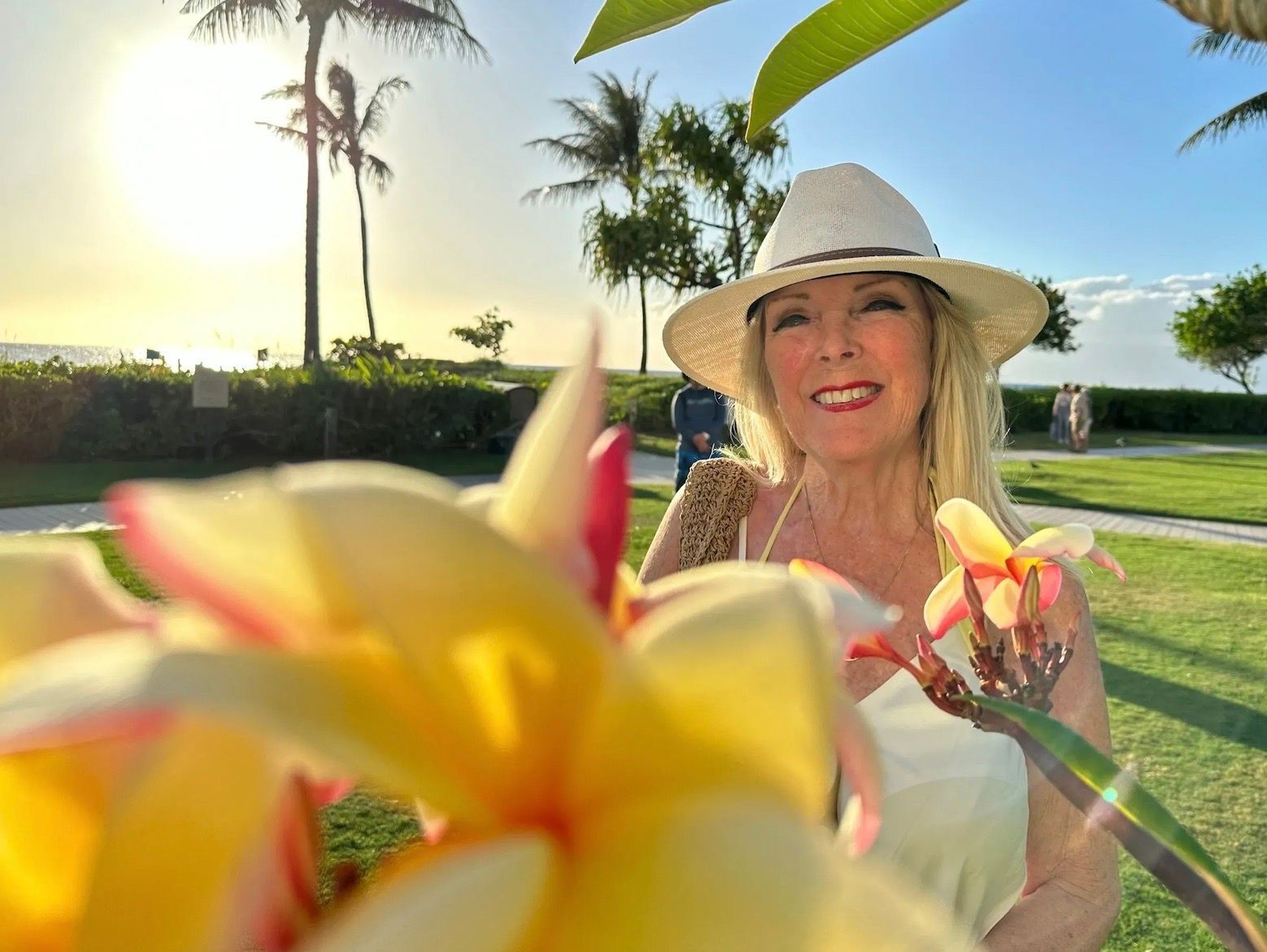 Woman in a white hat in warm sunset light, looking sideways outdoors with mountains in the background