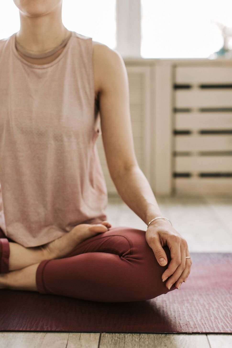 Person seated cross-legged on a yoga mat, meditating with hand in a mudra.