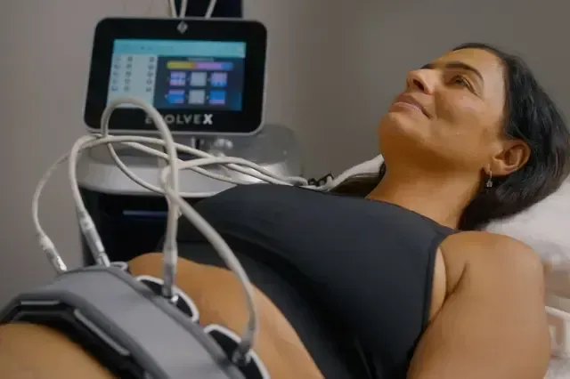 Woman lying on a treatment table with medical sensors attached and a monitoring device nearby
