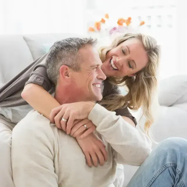 Smiling couple embracing on a white couch in a bright living room