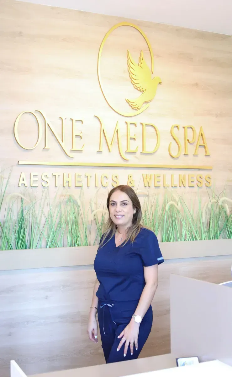 Woman standing in front of ONE MED SPA sign and green wall decor