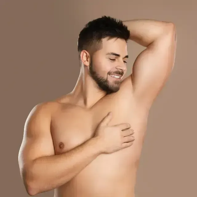 Smiling shirtless man posing with one arm raised against a plain tan background