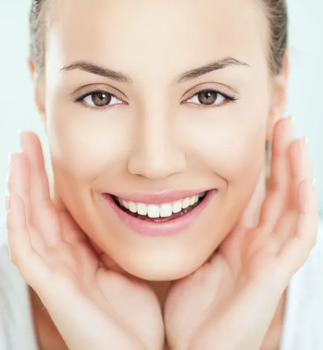 Smiling face with hands gently framing cheeks on a bright white background