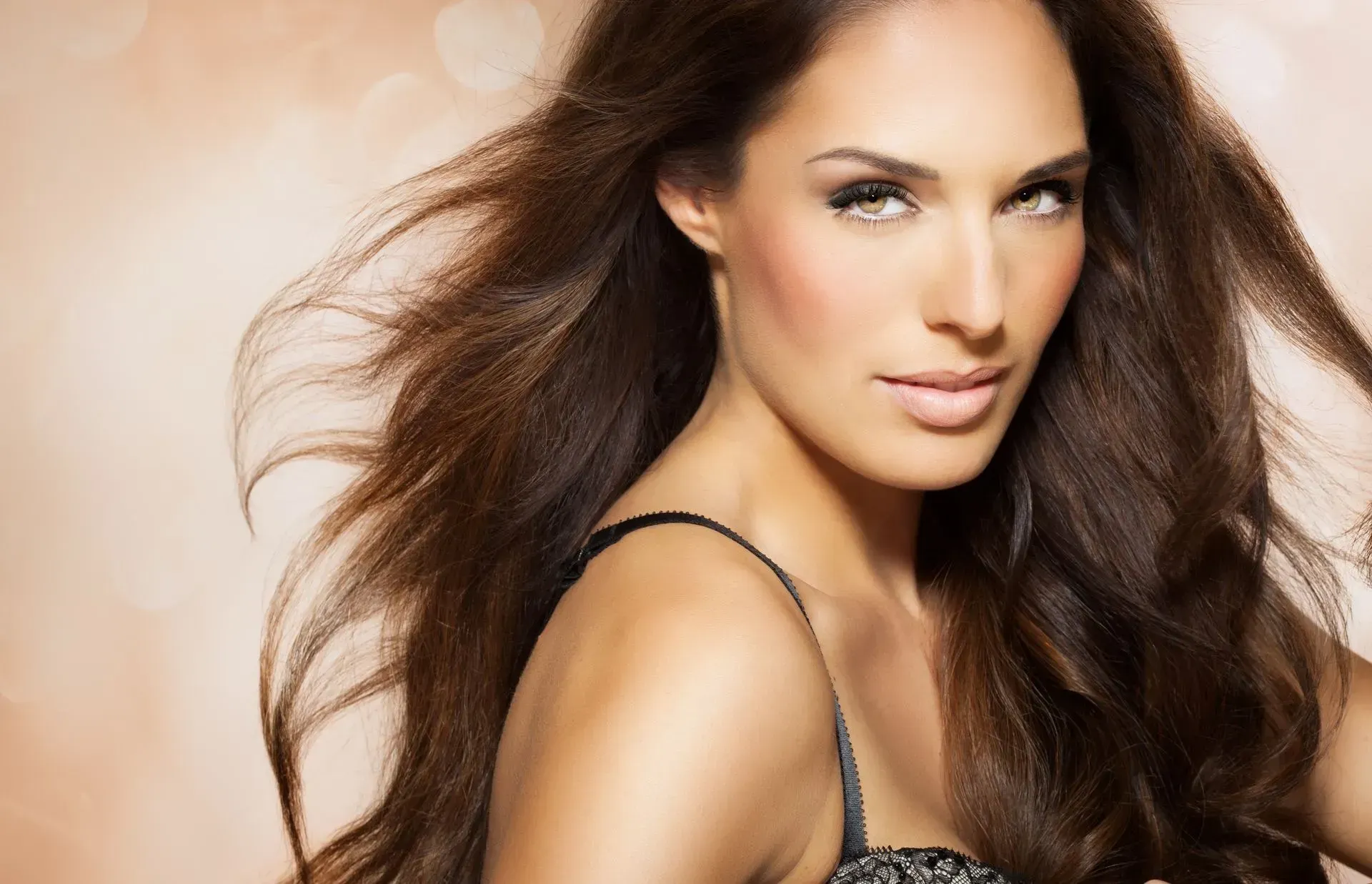 Close-up portrait of a woman with long brown hair against a soft beige background