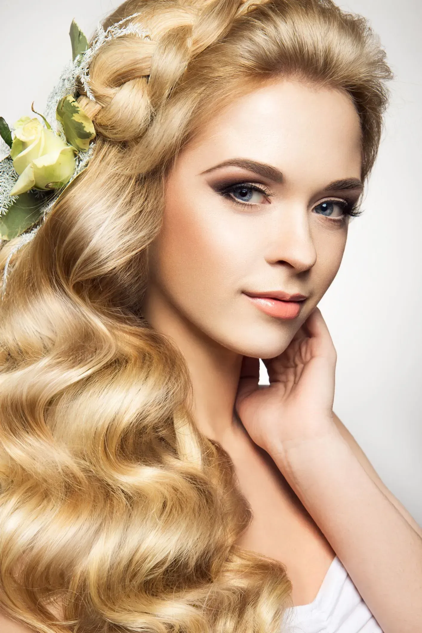 Portrait of a blonde woman with wavy hair, posing against a light background
