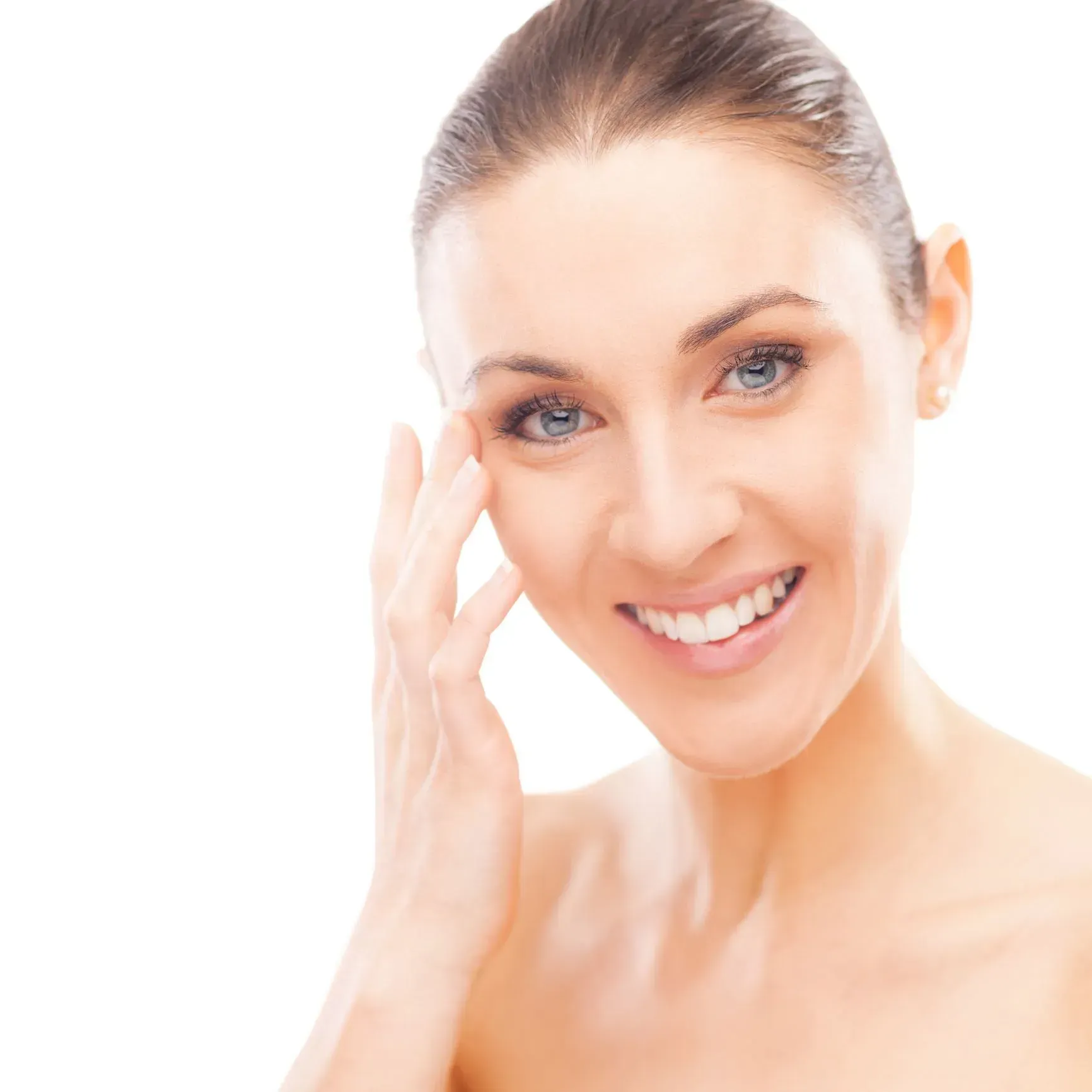 Smiling woman with hair pulled back, touching her face against a white background