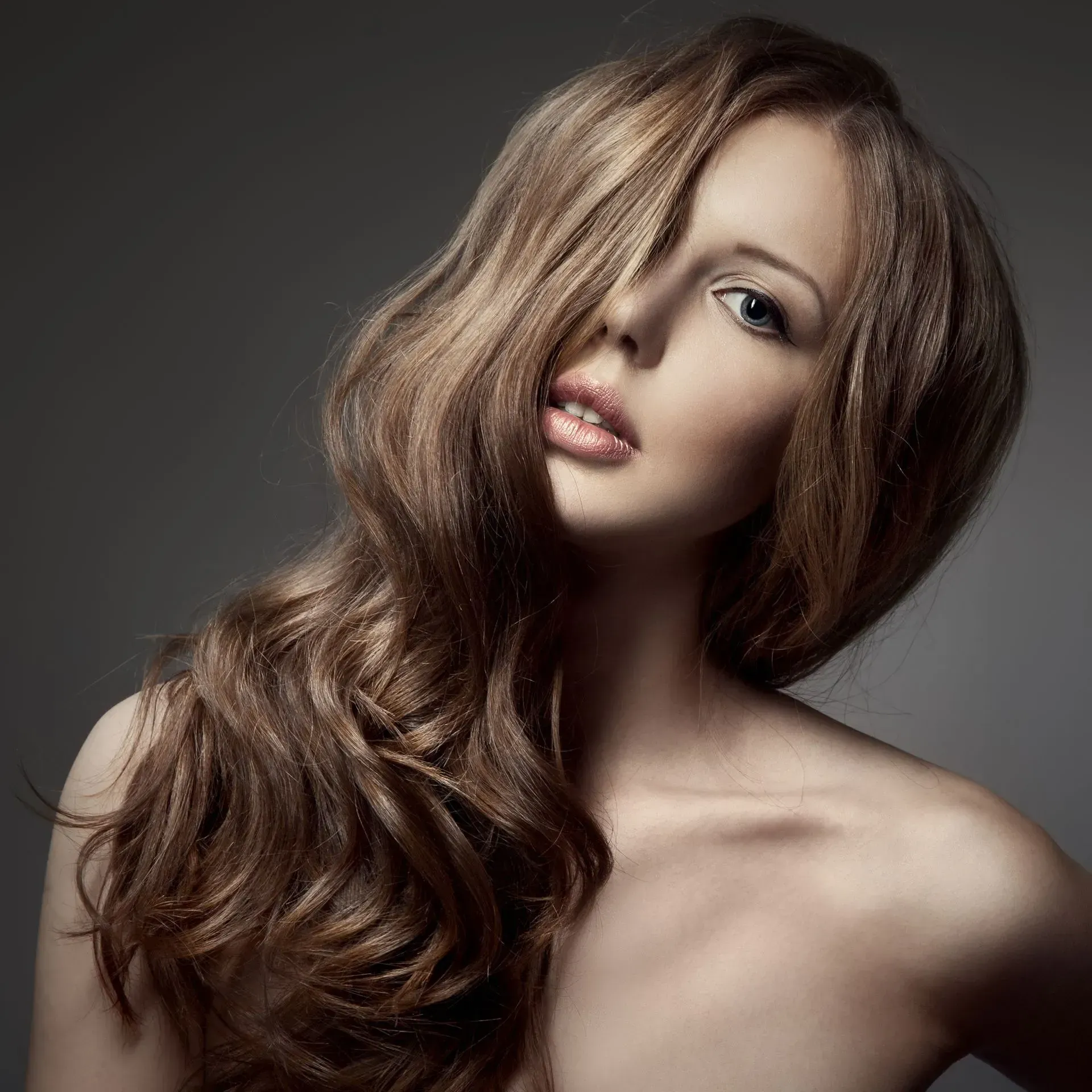 Portrait of a woman with long brown hair against a gray background