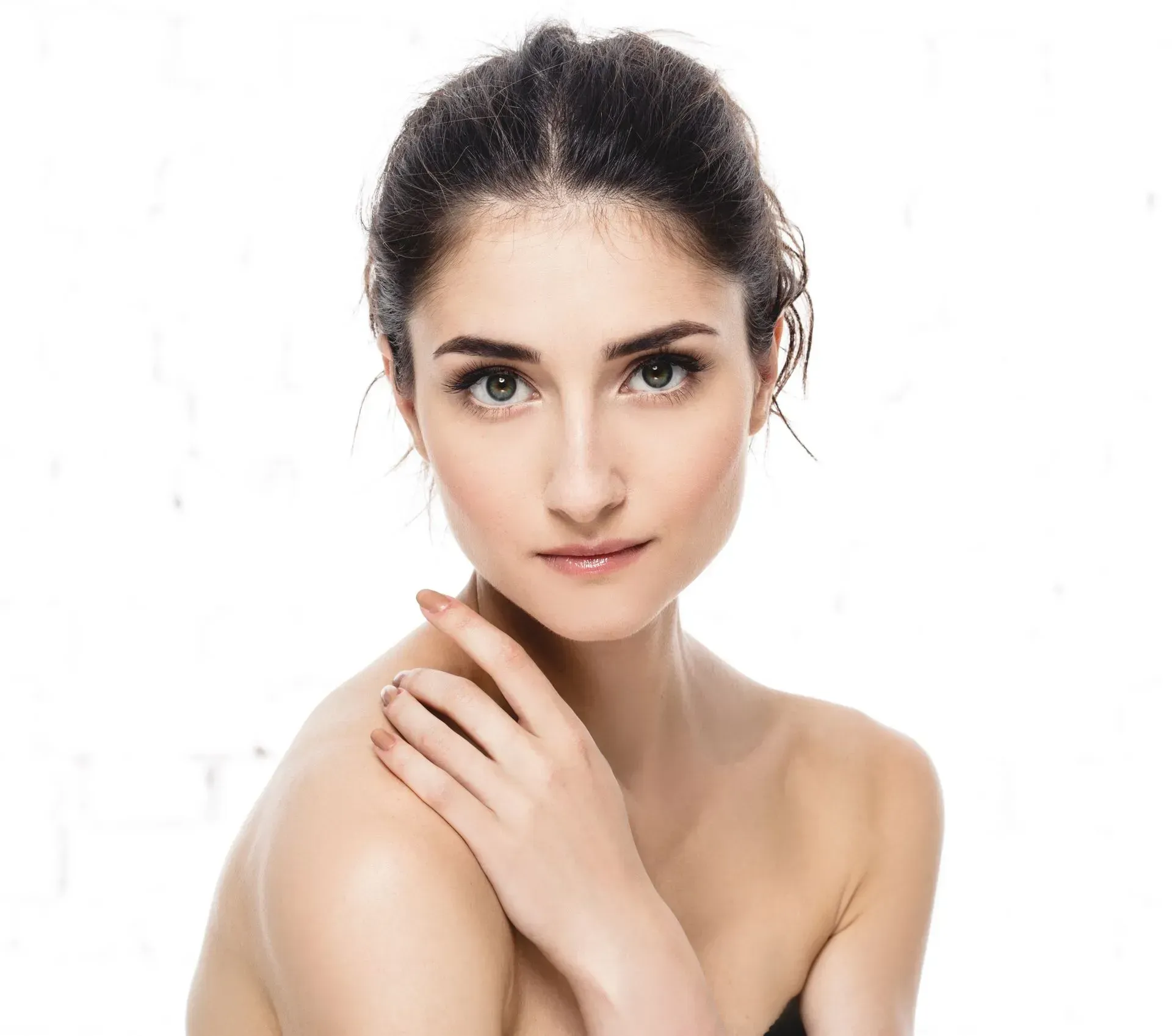 Portrait of a woman with dark hair, bare shoulders, and a calm expression on a white background