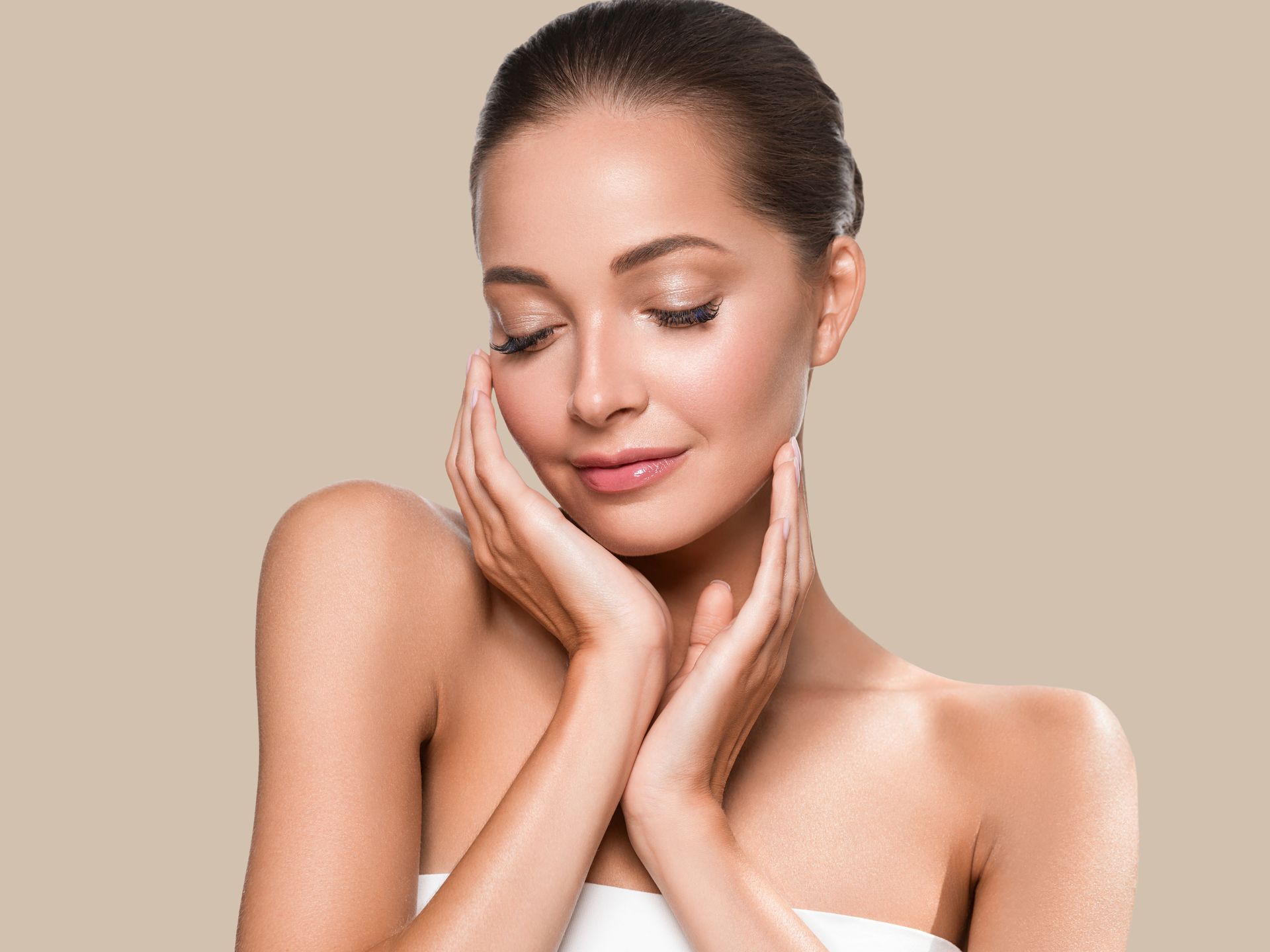 Woman with eyes closed, gently touching her face against a beige background.