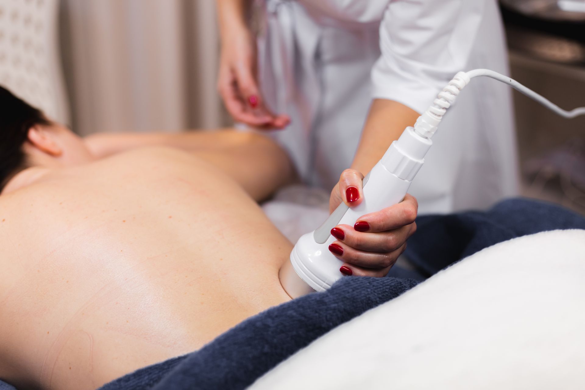 Spa therapist using a handheld device on a client's back during a treatment session