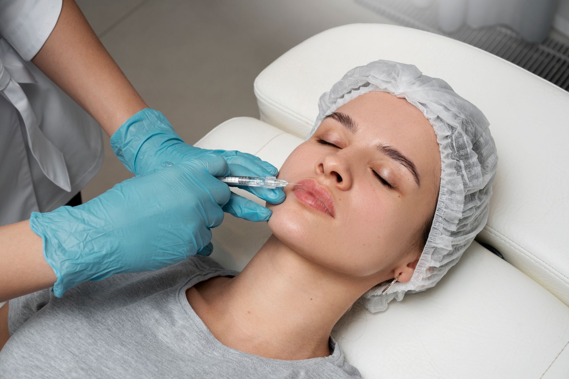 Cosmetic treatment applied to a woman’s lips with gloved hands in a spa setting