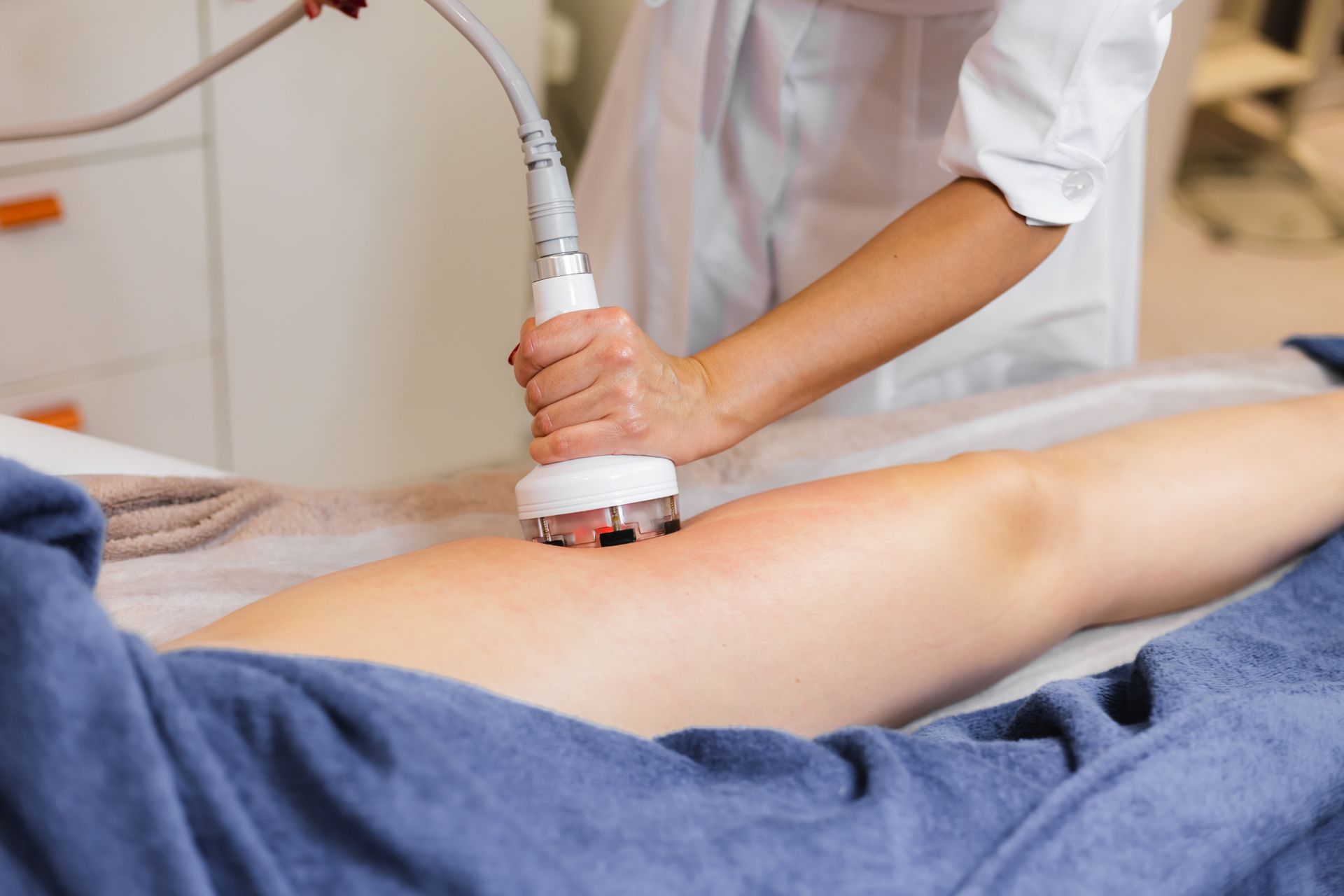 Therapist using a handheld device on a person’s leg during a spa treatment