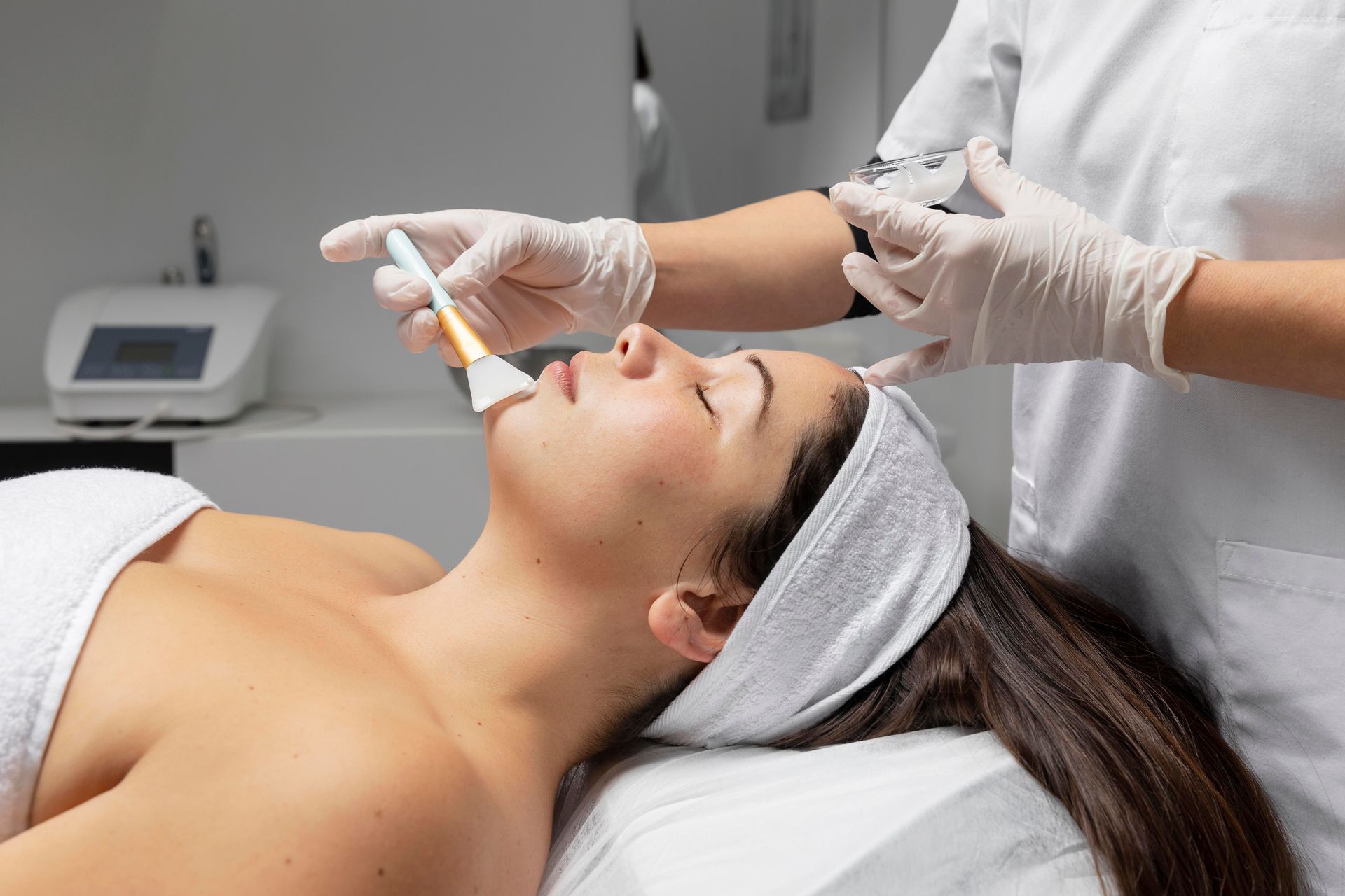 A facial treatment is being applied to a client lying on a spa bed.