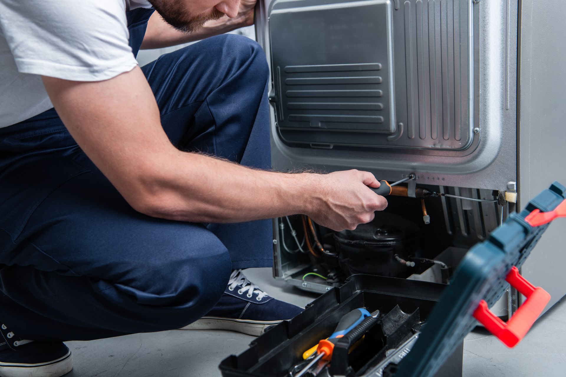 A man is repairing a refrigerator. A man is repairing a refrigerator.