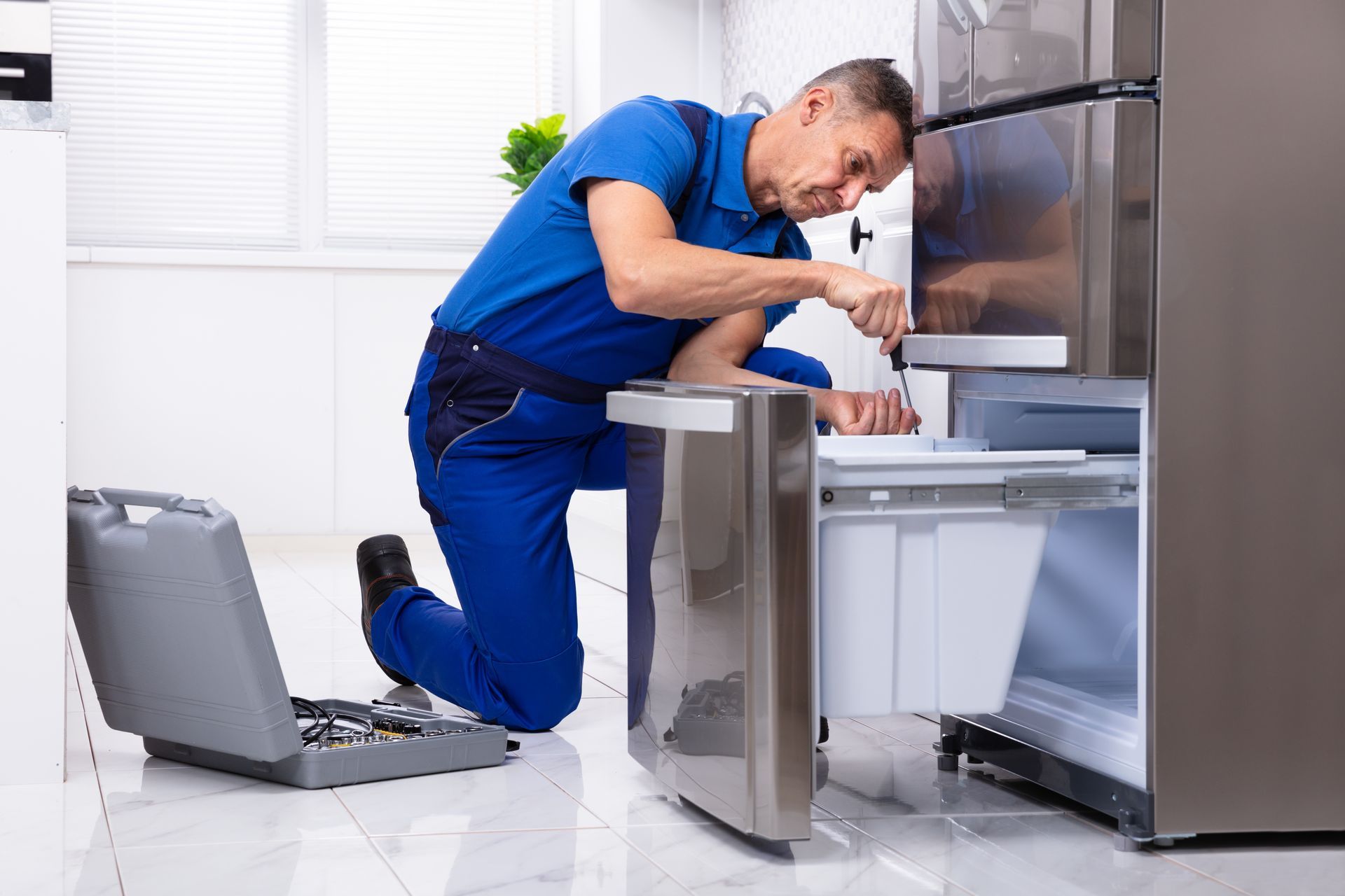 A technician is repairing a refrigerator. A technician is repairing a refrigerator.