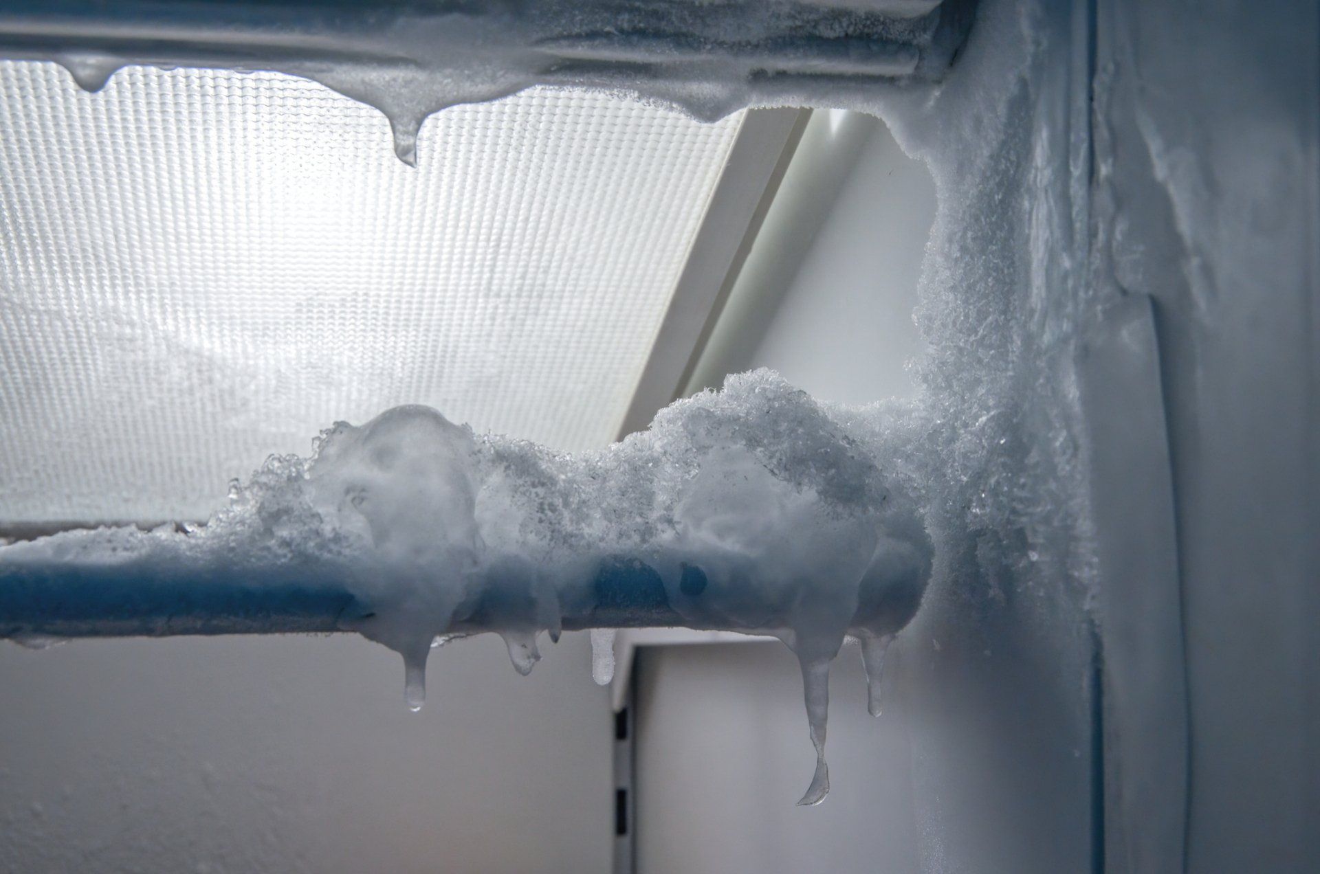 A freezer interior with thick ice buildup on the racks and walls.