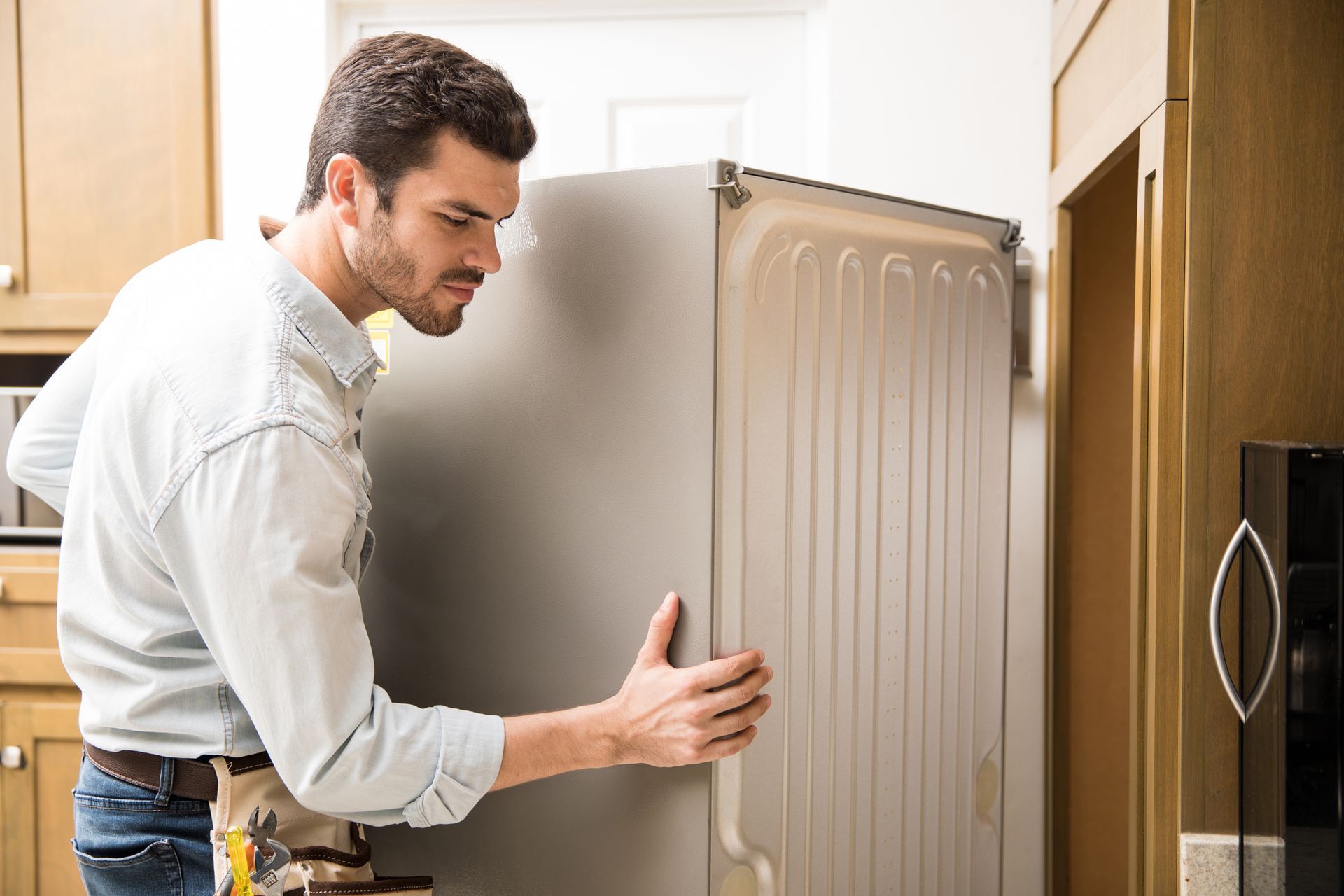 Technician installing a refrigerator in a kitchen for reliable professional appliance repair service.