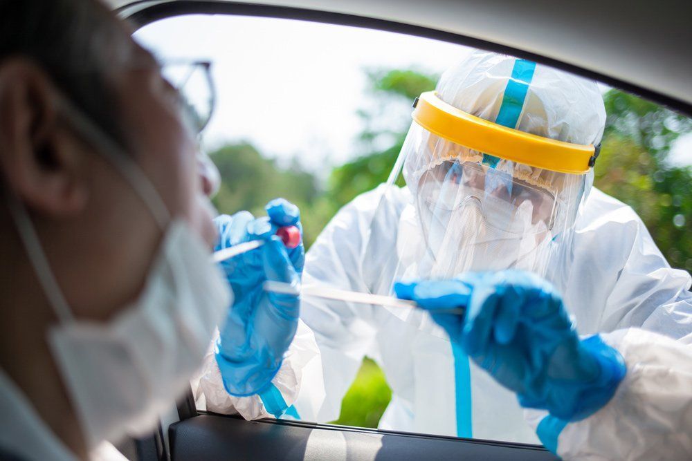 A man is getting a nasal swab from a nurse in a car.