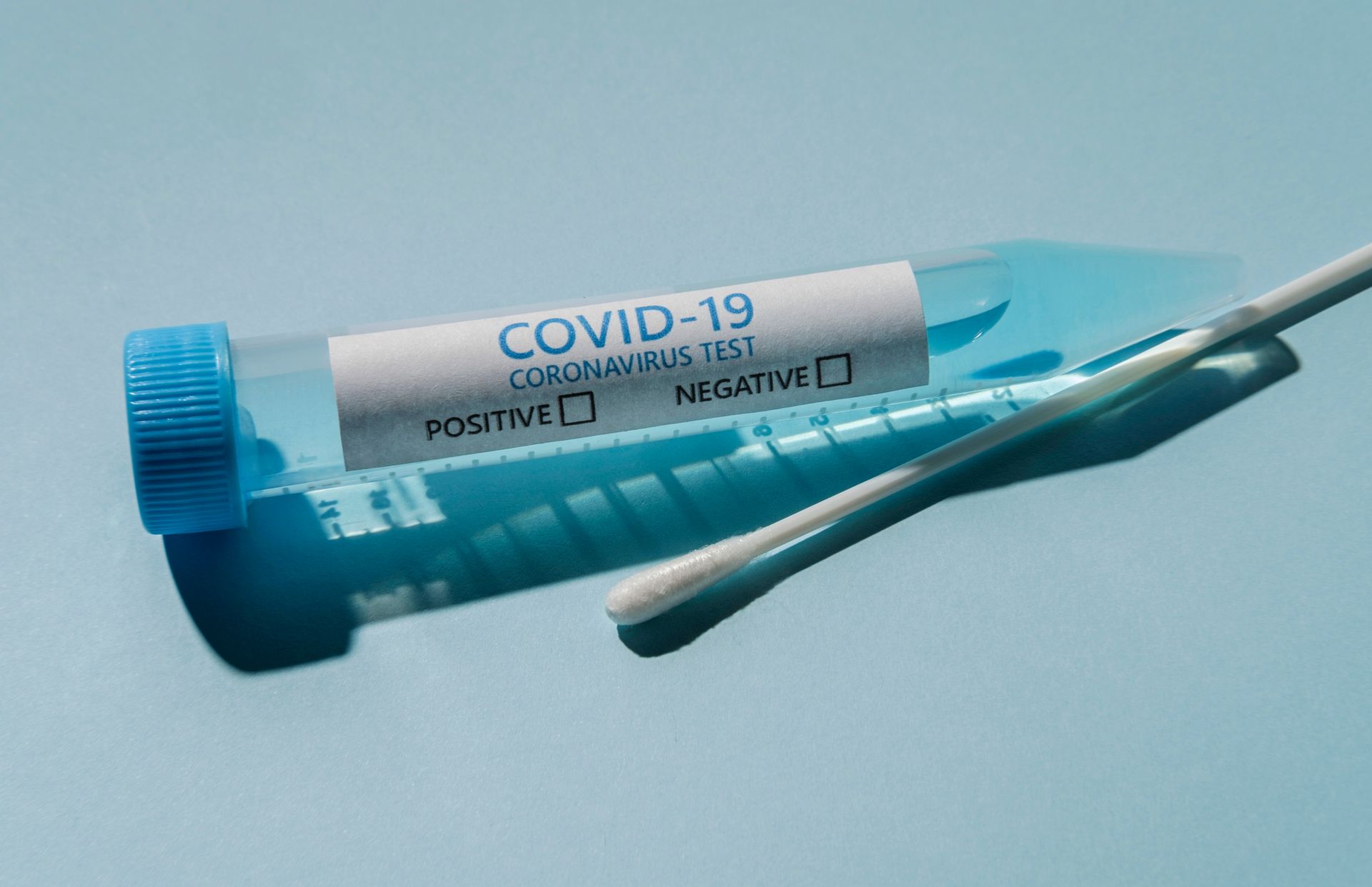 A covid-19 test tube with a swab sticking out of it.