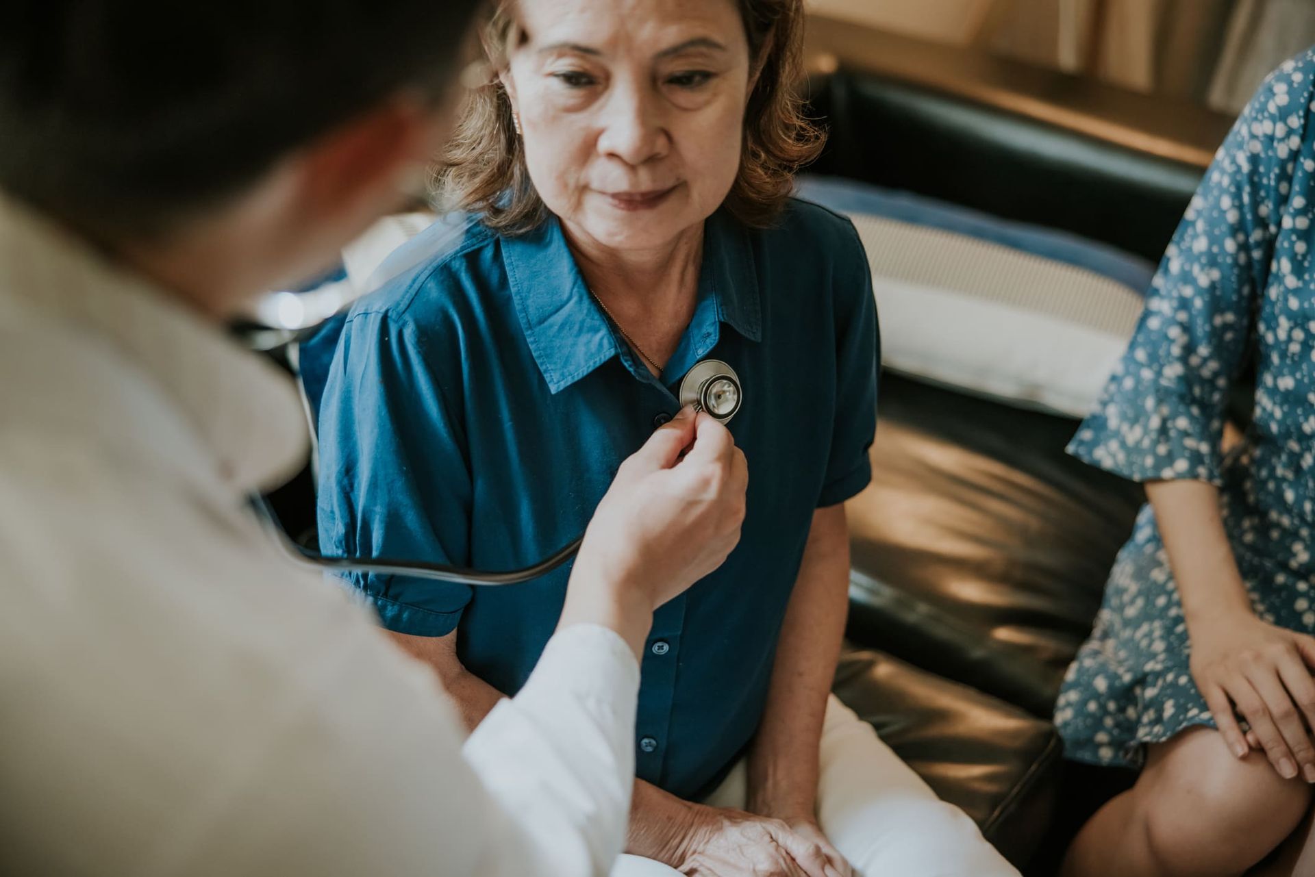 A doctor is listening to a woman 's heart with a stethoscope.