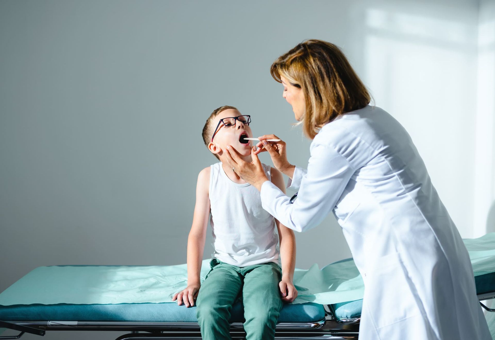 A female doctor examining a young boy's mouth