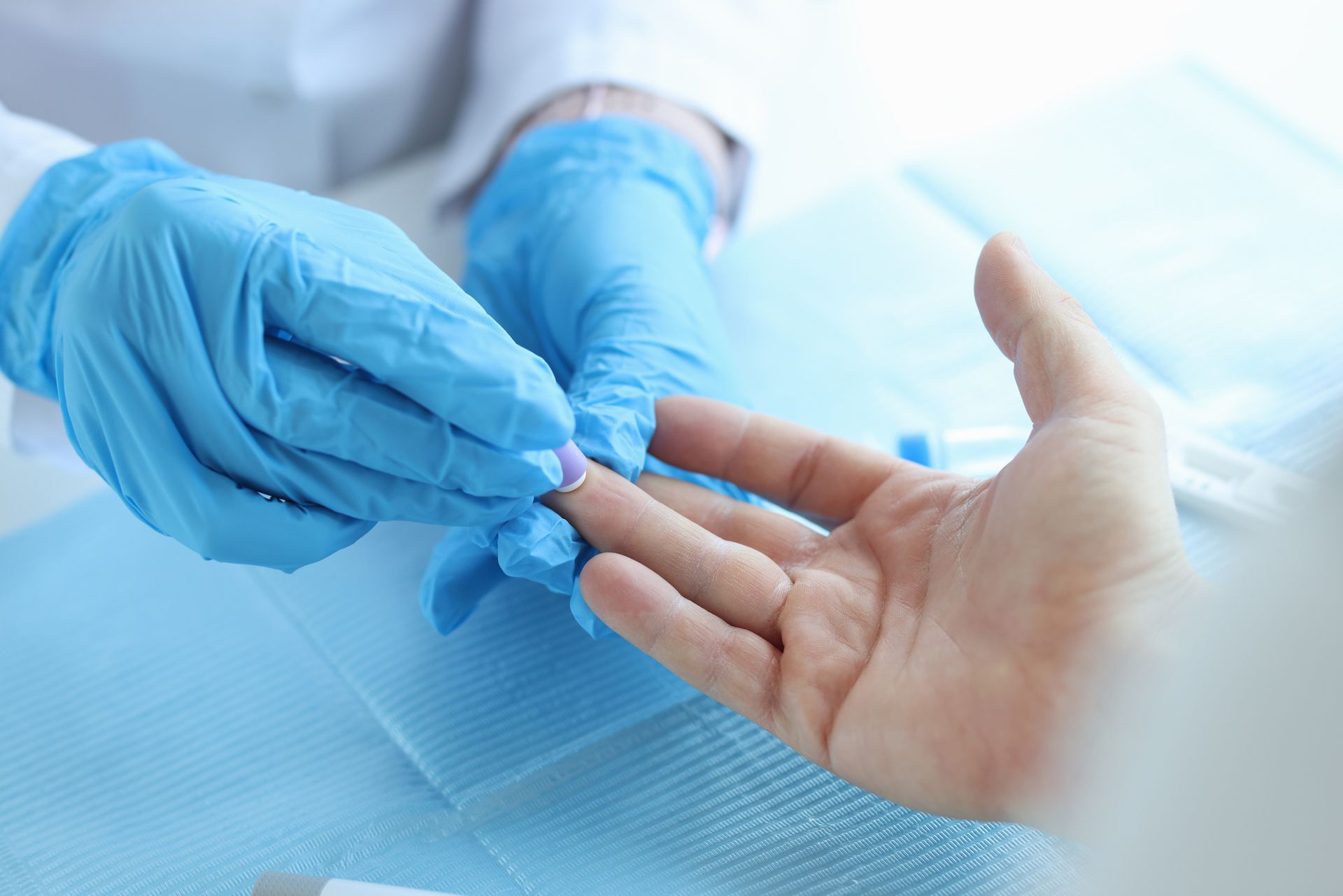 A hand wearing gloves extracting blood from a bare hand.