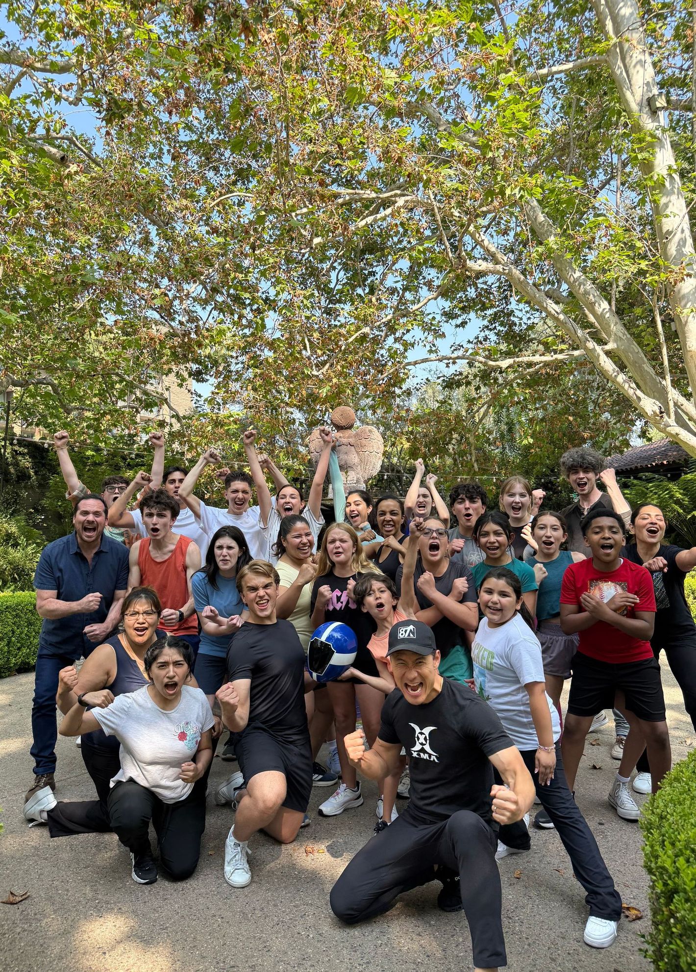 Group of people celebrating outdoors with raised arms and excited expressions.