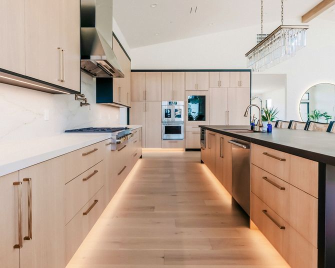 Modern kitchen with light wood cabinets, black countertops, and a bright open layout