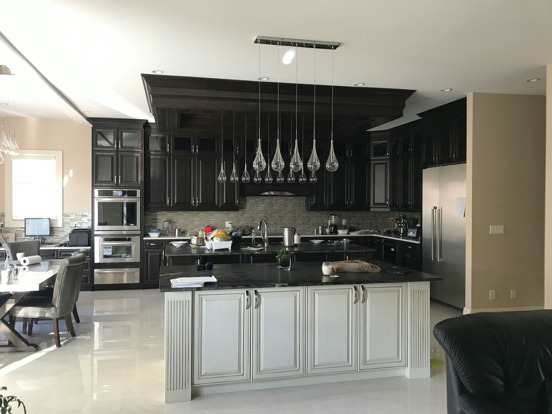 Modern kitchen with dark cabinets, black countertops, and a large island with hanging pendant lights.