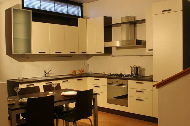 Cucina moderna con mobili bianchi, tavolo da pranzo nero ed elettrodomestici in acciaio inossidabile.