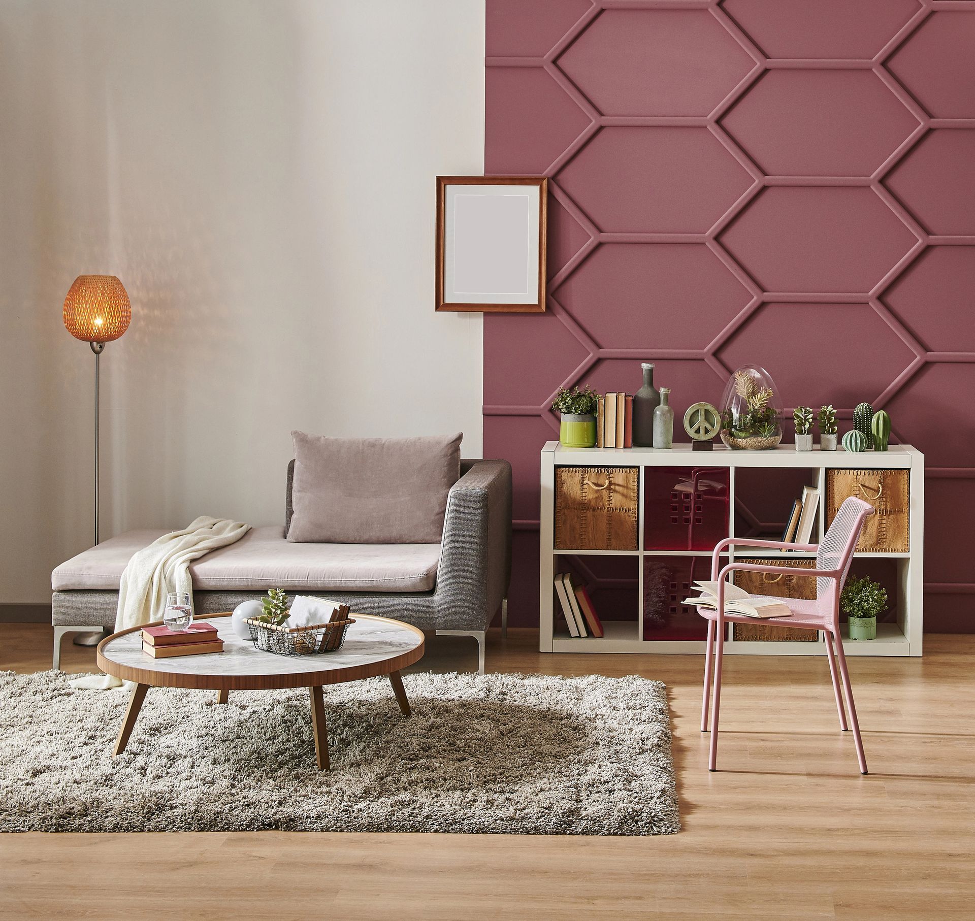 Soggiorno moderno con parete d'accento color malva, divano grigio, tavolino rotondo e poltrona rosa.