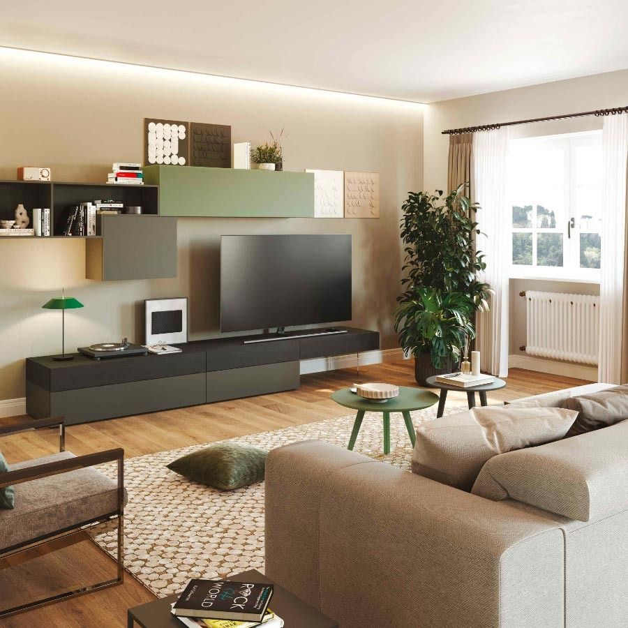 Soggiorno moderno con divano angolare grigio, TV a parete, piante e luce naturale che filtra dalle ampie finestre.
