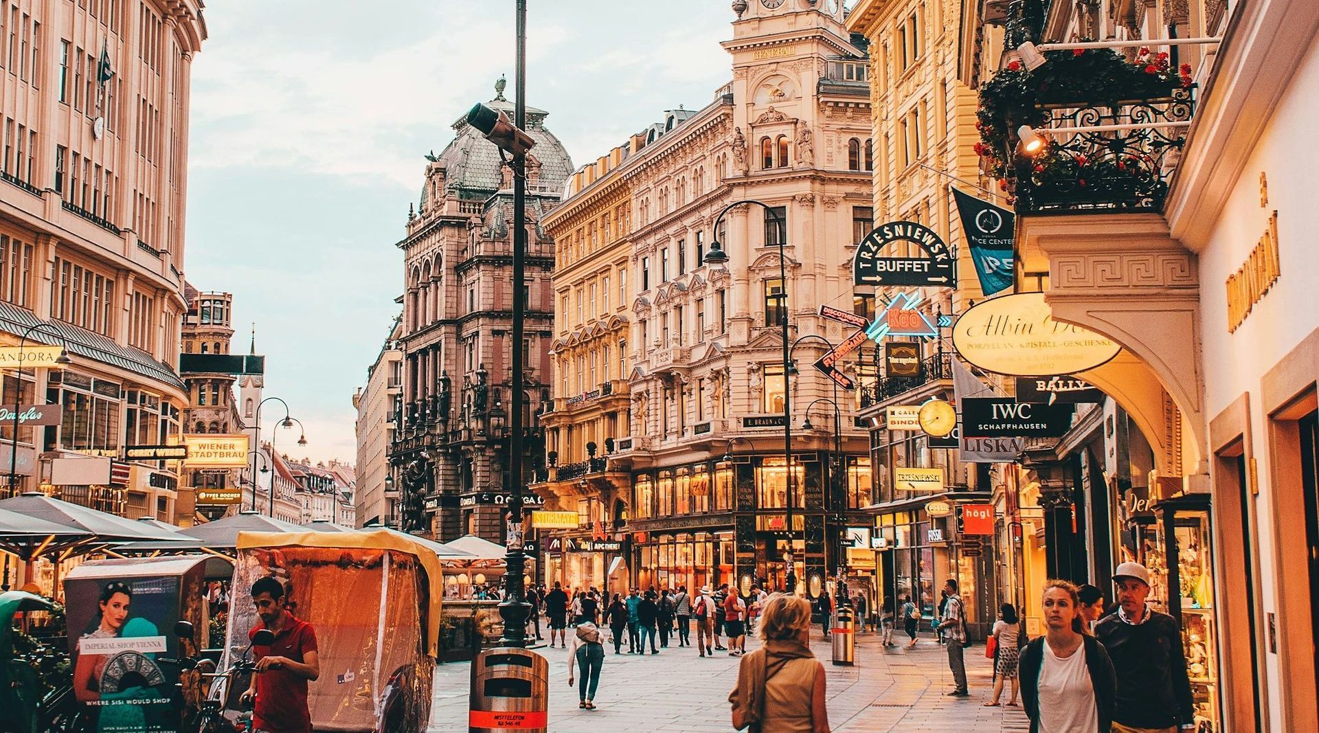Busy Kärntnerstrasse shopping street in central Vienna with people walking past historic buildings and cafés.