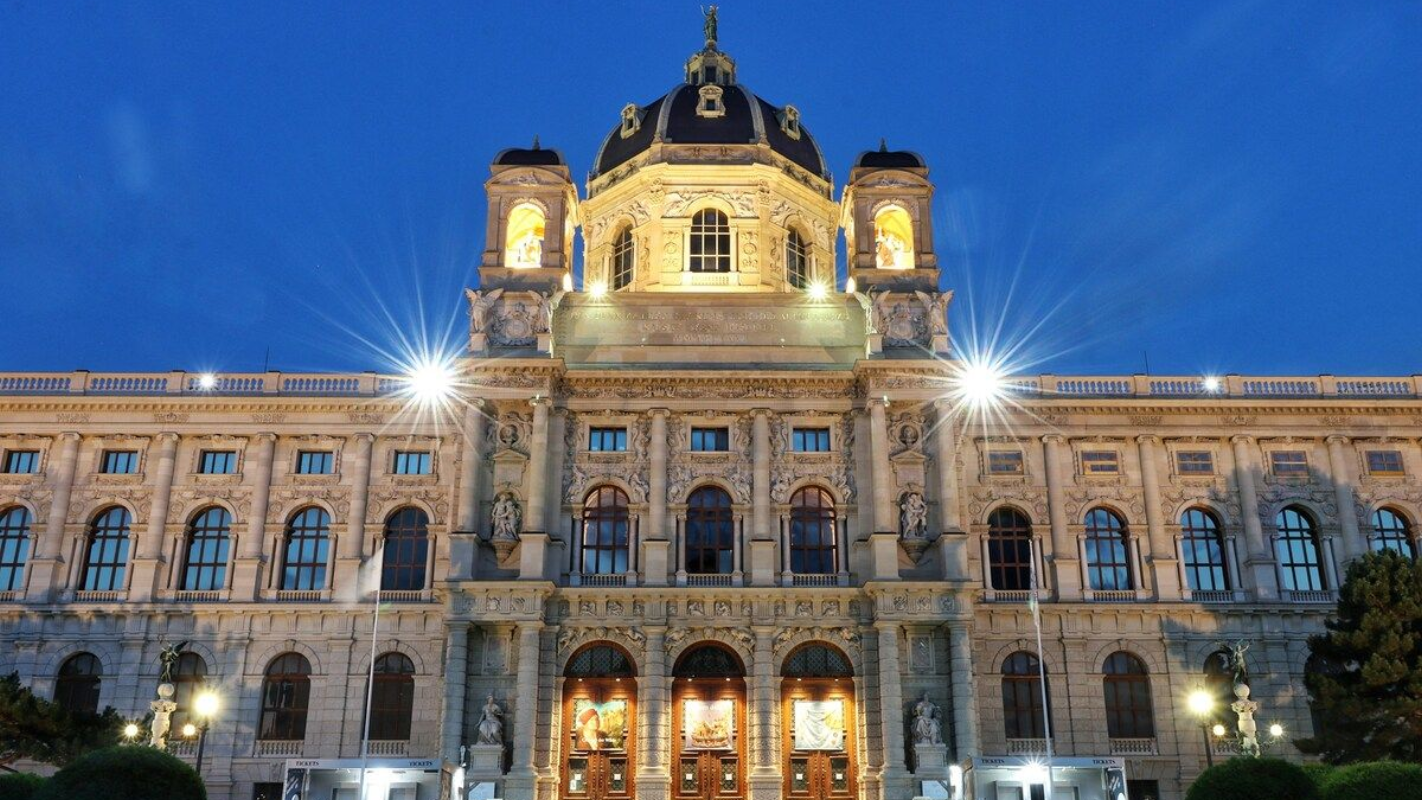 Front view of the Kunsthistorisches Museum in Vienna lit up against the evening sky