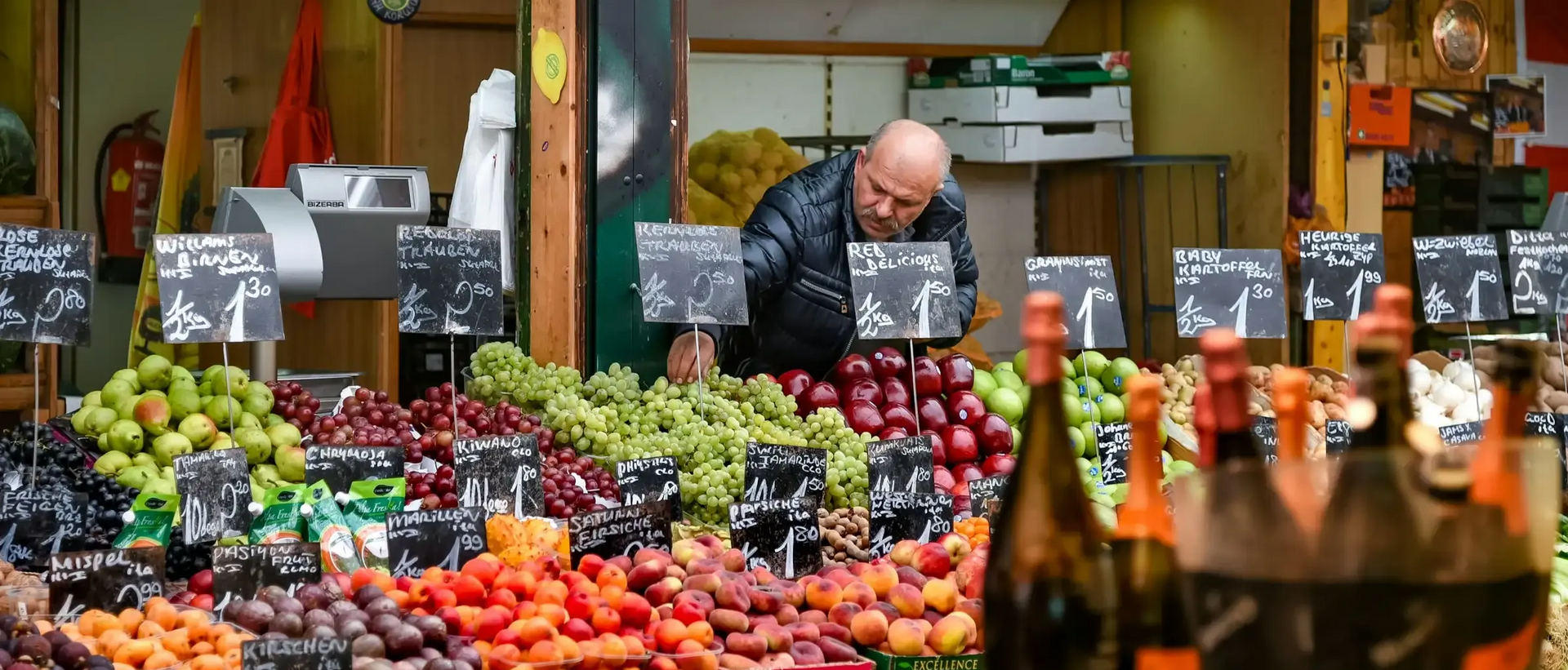 Colorful food stalls at Vienna’s Naschmarkt filled with spices, fruits, and people shopping on a sunny day.