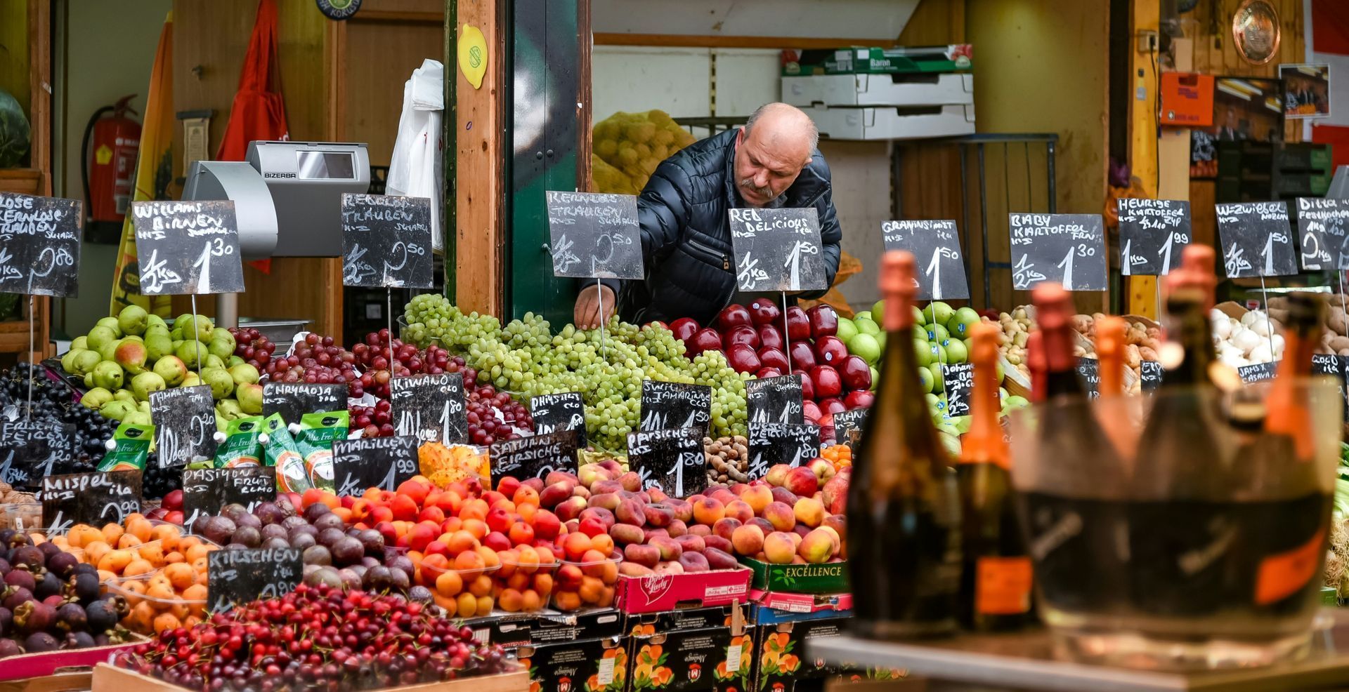 Colorful fruit and vegetable stands at Vienna’s Naschmarkt, with a vendor arranging produce at an open-air market.