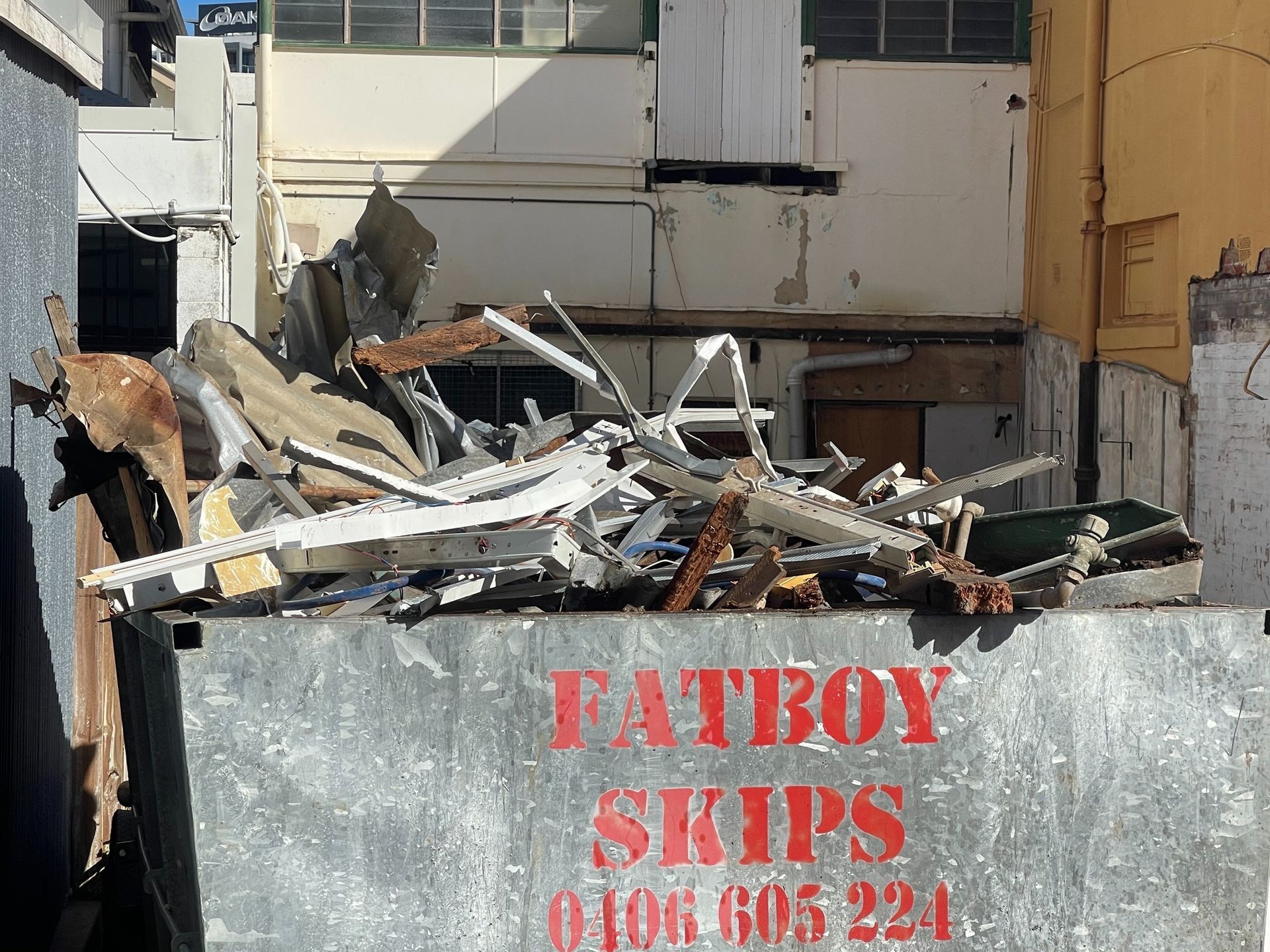 A Yellow Garbage Truck Is Driving Down A City Street — Fat Boy Skips Townsville In Nome, QLD
