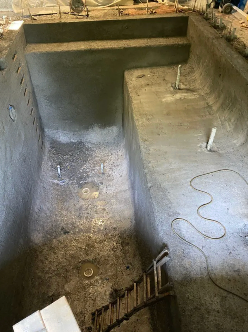 Interior concrete construction area with newly formed steps, plumbing pipes, and unfinished surfaces inside a home