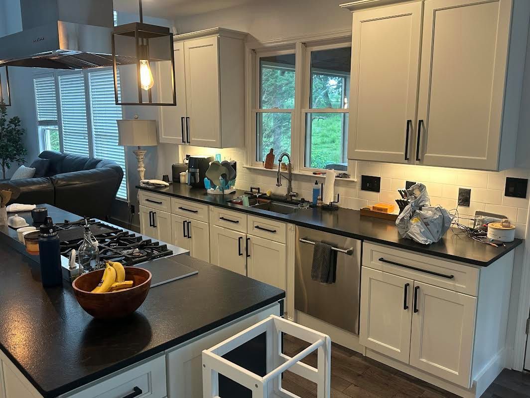 Bright modern kitchen with white cabinets, black countertops, and a central island with fruit bowl.