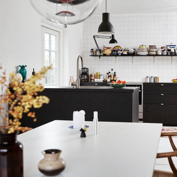 Modern kitchen with black cabinets, white island, and dining table in a bright minimalist interior
