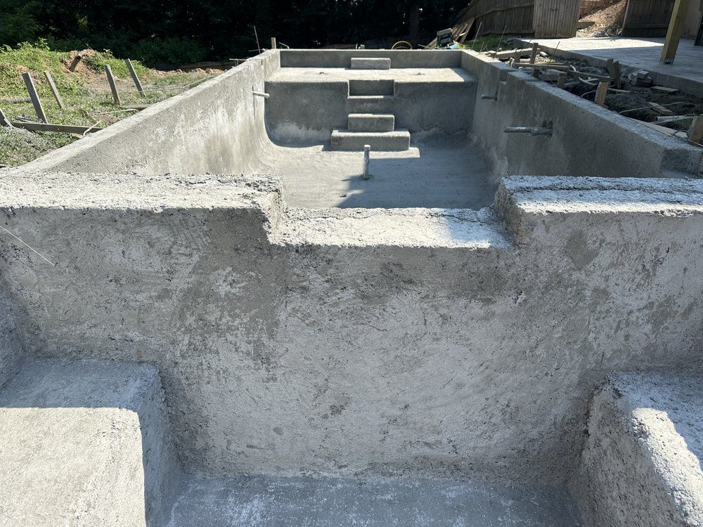 Concrete foundation with steps leading into a rectangular pit outdoors.
