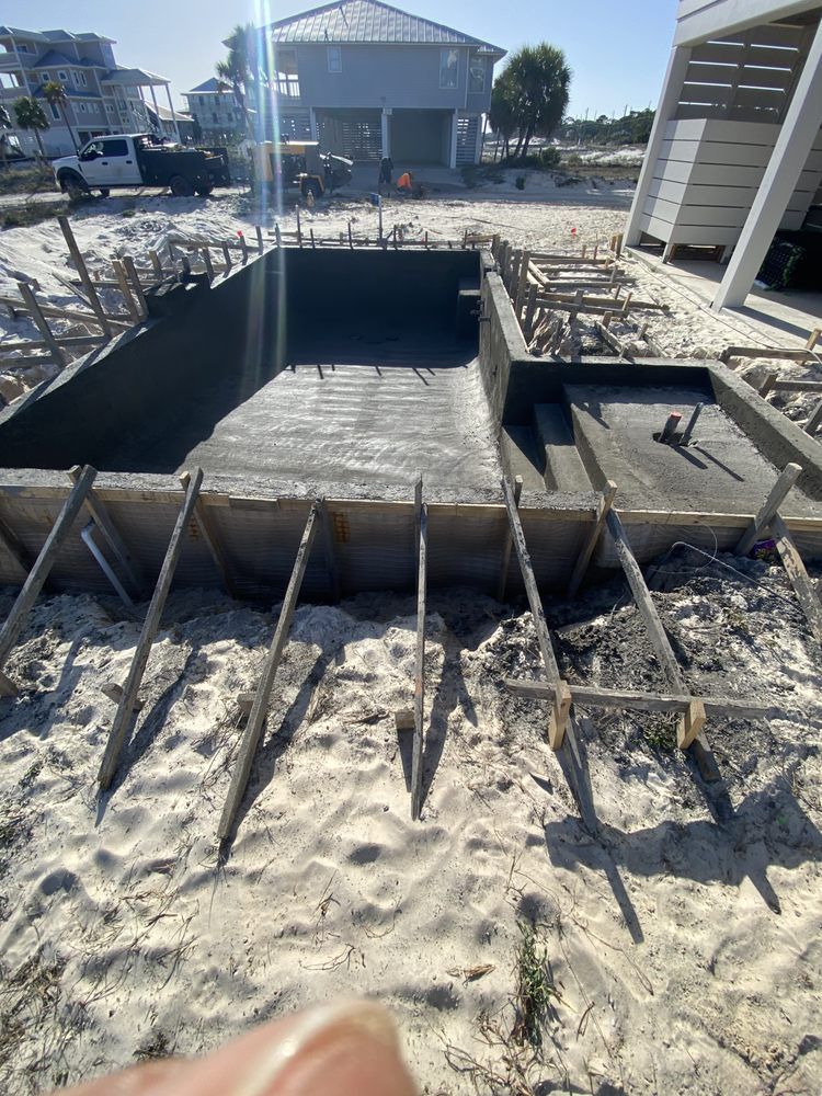 Beachside concrete pool under construction with wooden forms and steps, ocean in the background