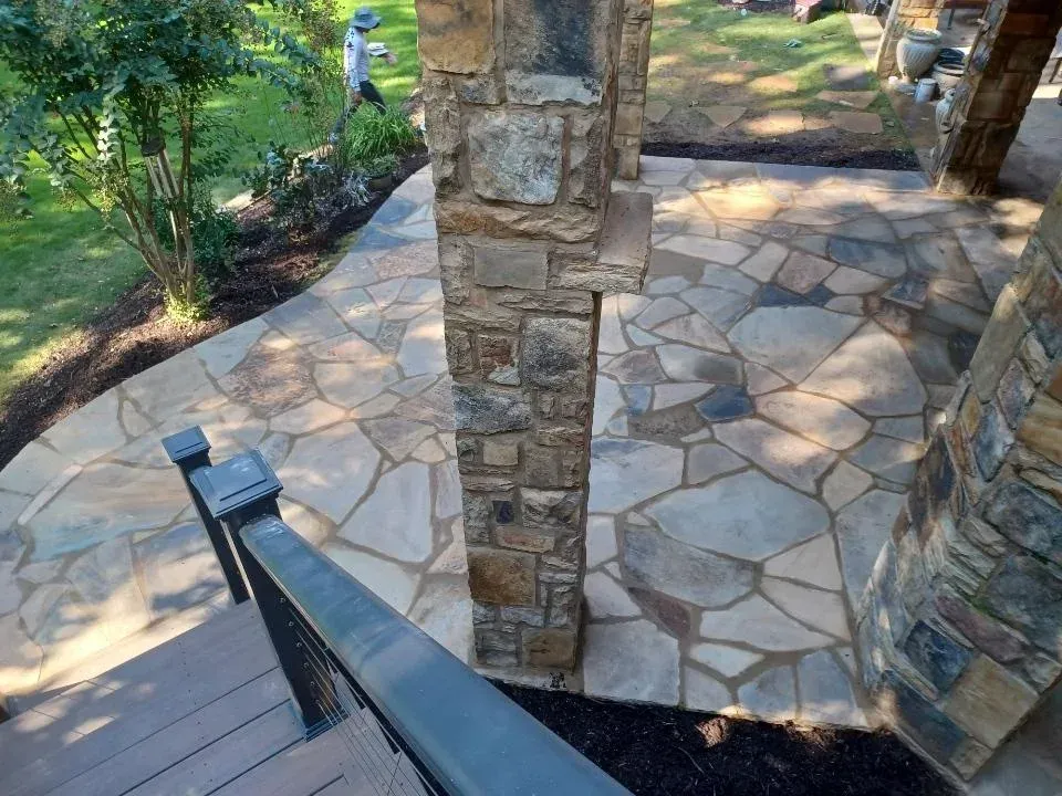 Stone patio with a central column and steps leading down to a landscaped garden path