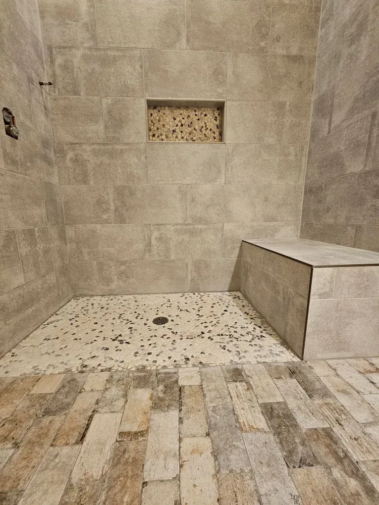 Stone-tiled shower with a bench and small recessed niche in the wall