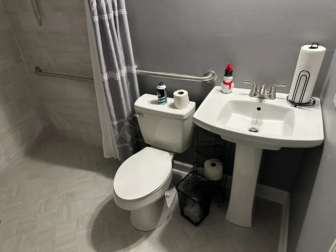 Small bathroom with toilet, sink, shower curtain, and toiletries on the sink and tank.