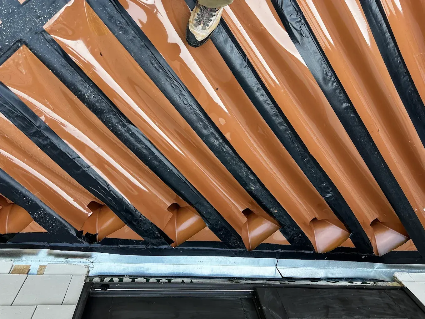 Orange and black roof tiles with a bird perched near the top edge
