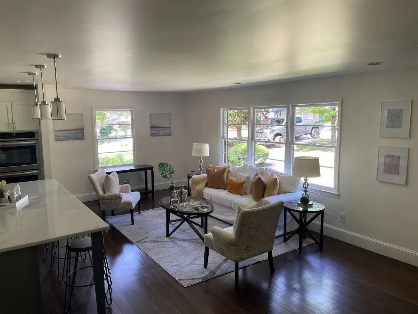 Bright living room with white sofa, chairs, coffee table, and large windows in open-concept home