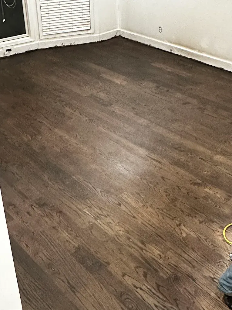 Empty room with dark wood flooring, white walls, and a window air conditioner.
