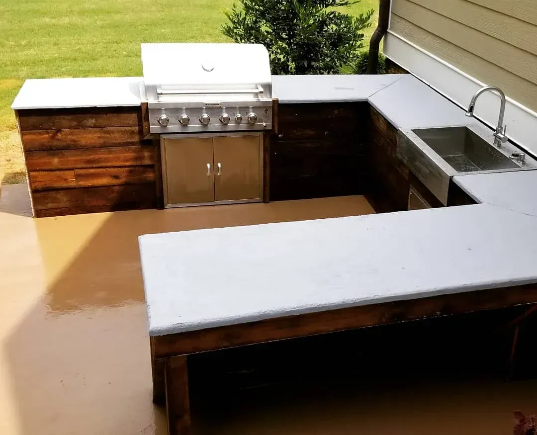Outdoor kitchen with a grill and sink, flooded with muddy water under a white countertop