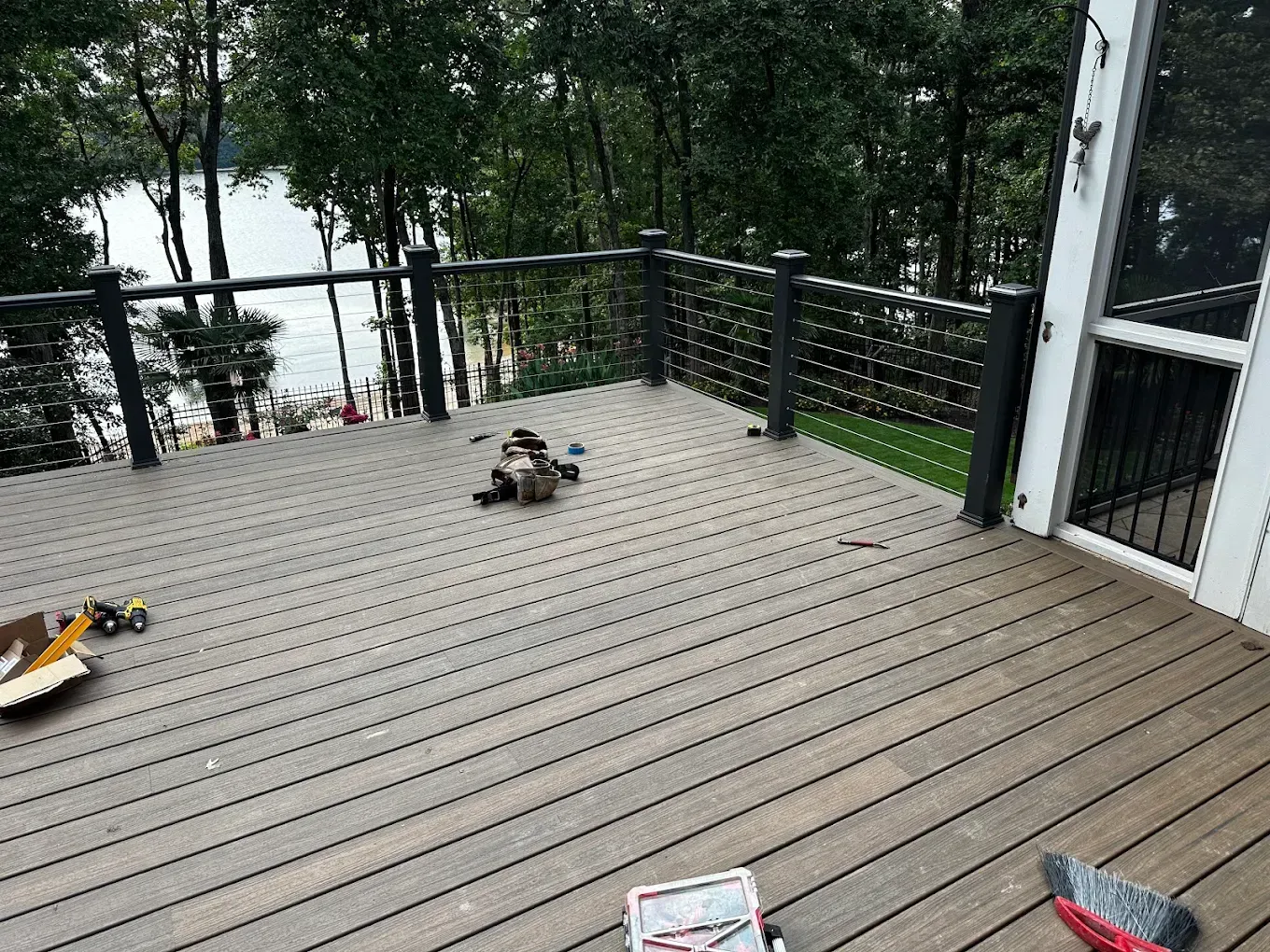Wooden deck overlooking a lake, with a small dog toy and scattered items on the floor.